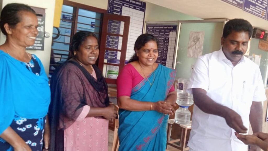 (From Left) Reena Saji, and Ancy Johnson look on as panchayat president Biju M A hands over the gold to its owner.