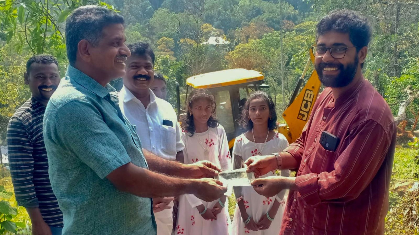 School Managing Committee Chairman G Biju handing over a cheque to House Construction Committee president Shiju Kumar. Also seen are the students - Arya and Meera.